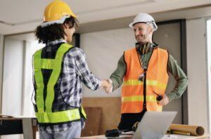 Two people in hard hats shaking hands